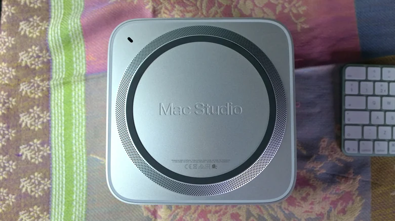 The Mac Studio M5 Ultra computer is shown from the bottom with the speaker and base