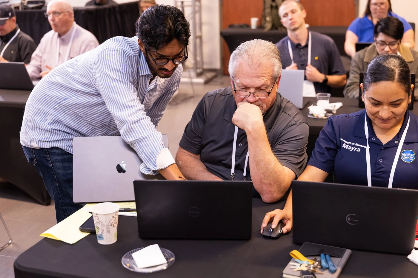 A facilitator leans over a laptop to guide participants during an OpenAI Academy workshop.