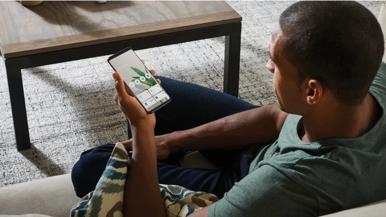 Person sitting on couch using old Android phone as dedicated smart-home control panel.