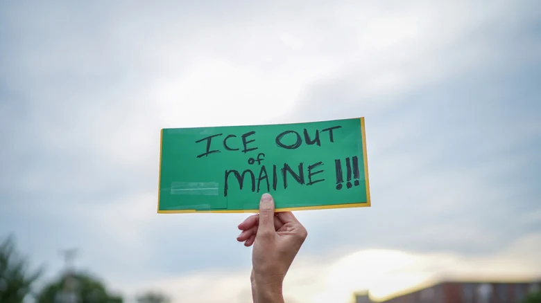 A protestor holding up a sign about ICE in Maine.
