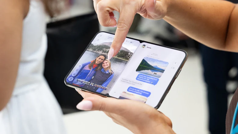 Finger pointing at an iPhone Duo, showing a camera roll of photo on the left and text messages on the right.